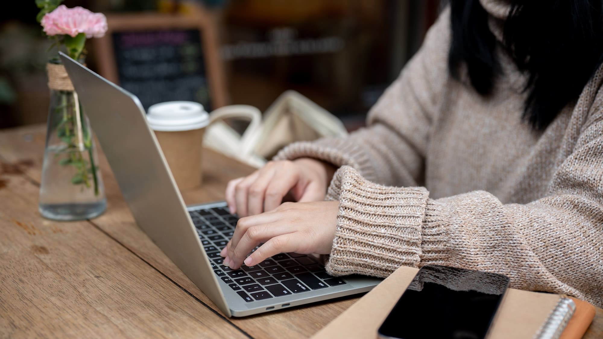 Woman sits in a cozy sweater at a computer working on her website while reading 'How To Find the Best Website Platform for your Small Business'