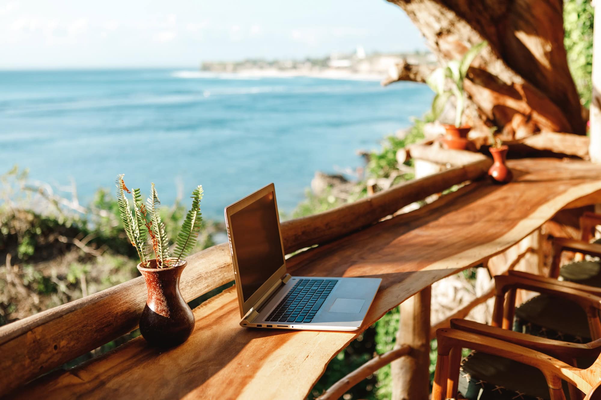 The Power of UX in Web Design- a laptop on a wooden desk space overlooking the ocean